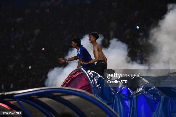 This picture taken on October 1, 2022 shows people reacting as tear gas is let off by police after a football match between Arema FC and Persebaya at...