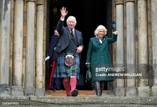 Britain's King Charles III, wearing a kilt, and Britain's Camilla, Queen Consort wave as they walk to meet members of the public after leaving from...
