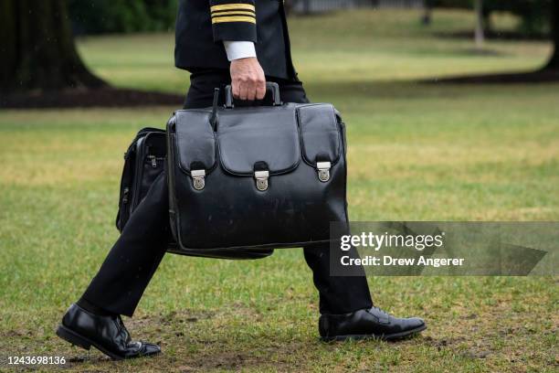 Military aide carries the "nuclear football," which contains launch codes for nuclear weapons, while walking to Marine One on the South Lawn of the...