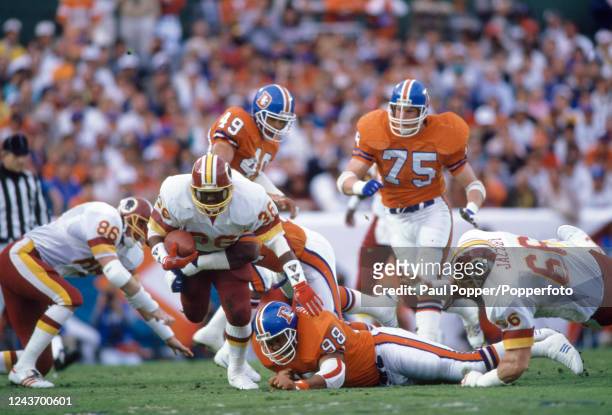 Timmy Smith of Washington Redskins avoids the challenge from Ricky Hunley of Denver Broncos during the Super Bowl XXII at the Jack Murphy Stadium on...