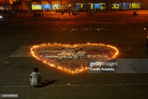 Football fans watch a candle flame shaped like a sign of love as condolences to the victims of the football match outside the Kanjuruhan Stadium in...