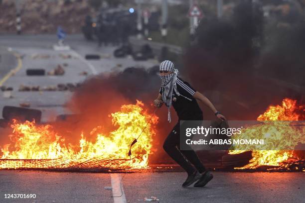 Palestinian youth runs away after throwing a rock with a slingshot at Israeli security forces during clashes at the northern entrance of the city of...