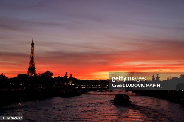 Boat sails on a Seine river by the Eiffel tower at sunset in Paris, on October 3, 2022.