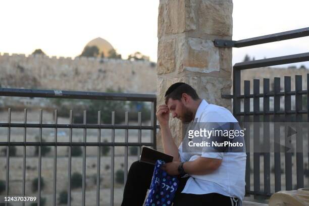 Jewish men pray in Jerusalem opposite the Al-Aqsa Mosque, the night before Yom Kippur, as their fast begins on Tuesday and ends on Wednesday, in...