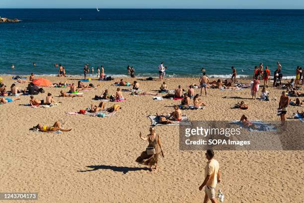 Beachgoers take advantage of an unusually hot October weekend walking along the Barceloneta beach or sunbathing under the sun.