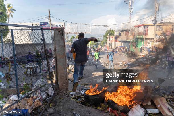 Man runs away from fire burning in the streets as demonstrators protest to demand the resignation of Prime Minister Ariel Henry, in the Petion-Ville...