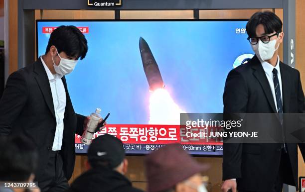 People walk past a television screen showing a news broadcast with file footage of a North Korean missile test, at a railway station in Seoul on...