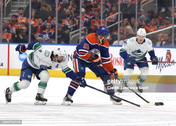 Evander Kane of the Edmonton Oilers skates the puck against Conor Garland of the Vancouver Canucks on October 3, 2022 at Rogers Place in Edmonton,...