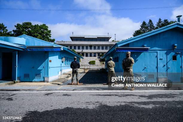 Soldiers and a South Korean soldier stand guard before North Korea's Panmon Hall and the military demarcation line separating North and South Korea,...