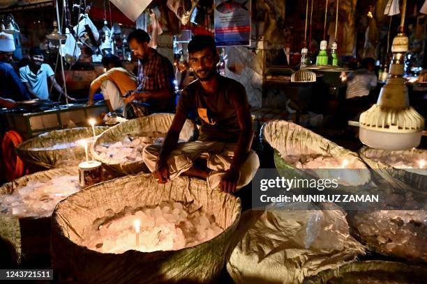 Vendors use candles at a fish market during a power blackout in Dhaka on October 4, 2022. - At least 130 million people in Bangladesh were left...