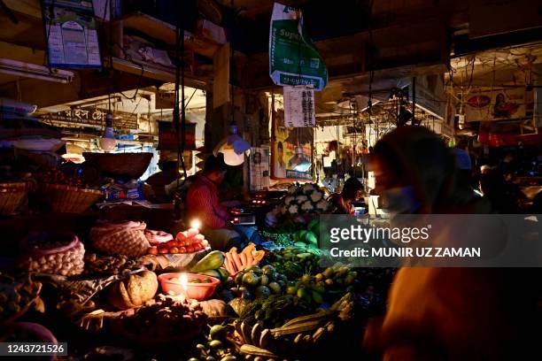 Vendors use candles at a vegetable market during a power blackout in Dhaka on October 4, 2022. - At least 130 million people in Bangladesh were left...