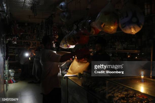 Worker uses a candle to continue business during the power outage in Dhaka, Bangladesh, on Tuesday, Oct. 4, 2022. Nearly half of Bangladesh was left...