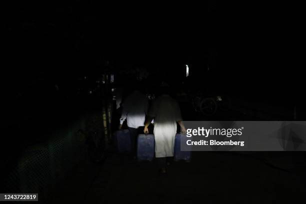People carry fuel in containers on a dark street during the power outage in Dhaka, Bangladesh, on Tuesday, Oct. 4, 2022. Nearly half of Bangladesh...