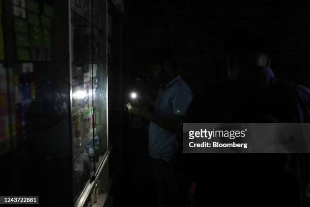 Pharmacy worker uses a mobile torch to continue business during the power outage in Dhaka, Bangladesh, on Tuesday, Oct. 4, 2022. Nearly half of...