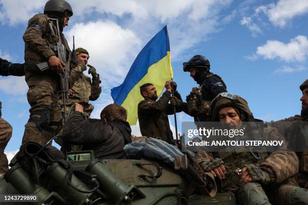 Ukrainian soldiers adjust a national flag atop a personnel armoured carrier on a road near Lyman, Donetsk region on October 4 amid the Russian...