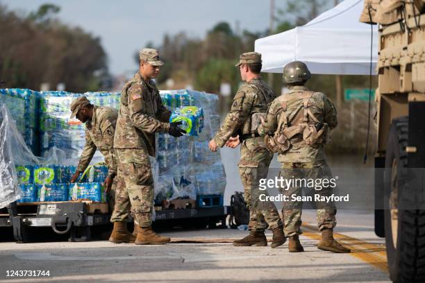 National Guardsmen move cases of water near a flooded road in the wake of Hurricane Ian near the Peace River on October 4, 2022 in Arcadia, Florida....