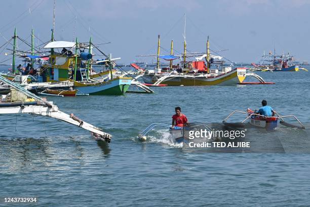 In this photo taken on August 20 crew on outriggers sail past fishing "mother" boats in the village of Cato, Infanta town, Pangasinan province, as...