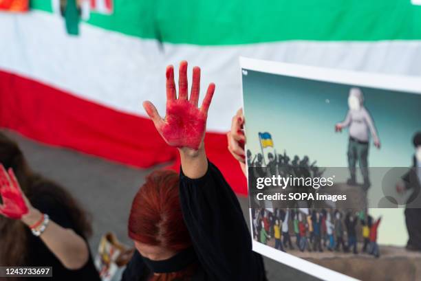 Female protester raises a red painted hand against the Iranian flag during the demonstration. Similar demonstrations were held in cities across the...