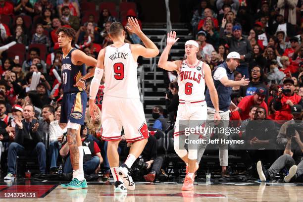 Nikola Vucevic hi-fives Alex Caruso of the Chicago Bulls during the game against the New Orleans Pelicans on October 4, 2022 at United Center in...