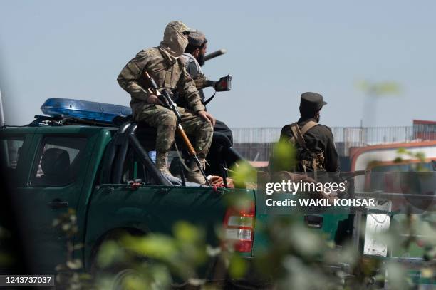 Taliban security personnel sit on the back of a vehicle as firefighters try to extinguish a fire at a business centre mall in Kabul on October 5,...