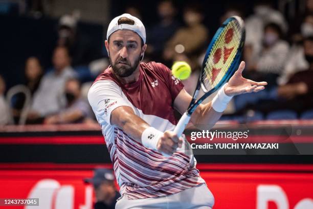 Steve Johnson of the US hits a return against Denis Shapovalov of Canada during their men's singles match at the Japan Open tennis tournament in...