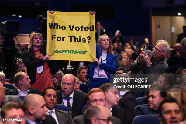 Activists hold a Greenpeace banner reading 'Who voted for This' as Britain's Prime Minister Liz Truss delivers her keynote address on the final day...