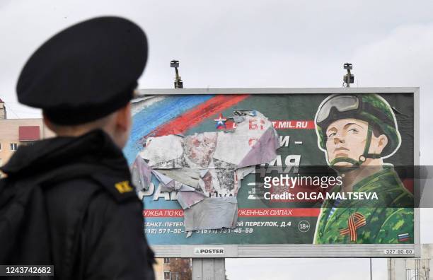 Military cadet stands in front of a billboard promoting contract army service in Saint Petersburg on October 5, 2022. - Russian President Vladimir...