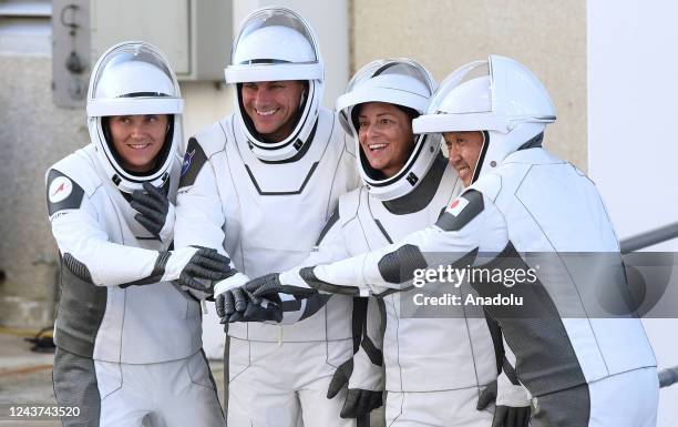 Russian cosmonaut Anna Kikina, NASA astronauts Josh Cassada and Nicole Mann, and Japanese astronaut Koichi Wakata join hands as they walk out of the...