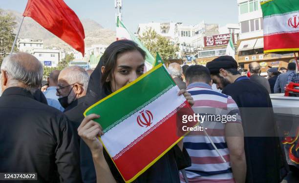 An Iranian woman lifts a national flag at a pro-government rally in Tajrish square north of Tehran, on October 5 condemning recent anti-government...