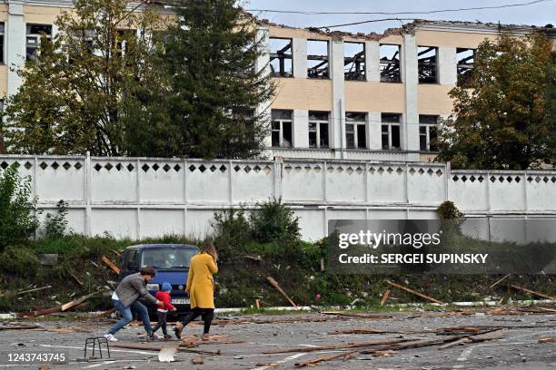 Family walks past a building destroyed by Russian, Iranian-made, drones after an airstrike on Bila Tserkva, southwest of Kyiv, on October 5 amid the...