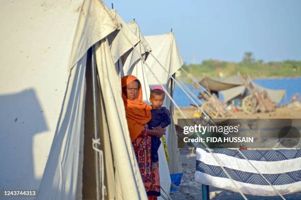 Displaced flood-affected woman stands with her child at a makeshift camp alongside flood waters at Dera Allah Yar in Jaffarabad district of...