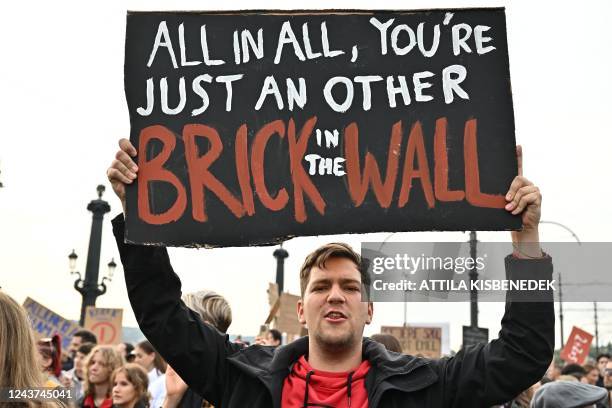 Young man holds up a placard with a quote from Pink Floyd's song "Another Brick in the Wall" as students, teachers and sympathizer block the traffic...