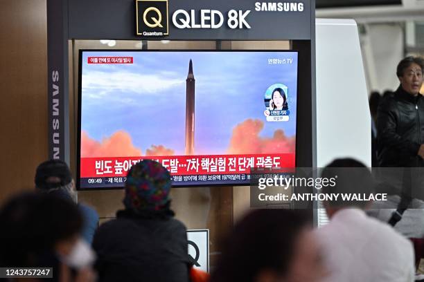 People sit near a television showing a news broadcast with file footage of a North Korean missile test, at a railway station in Seoul on October 6,...