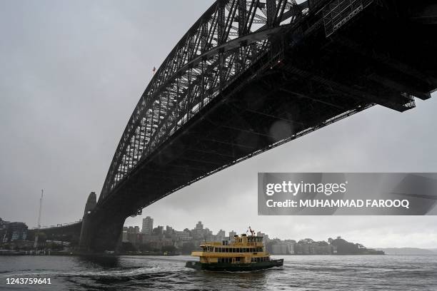 Ferry sails under the Harbour Bridge while it rains in Sydney on October 6, 2022.