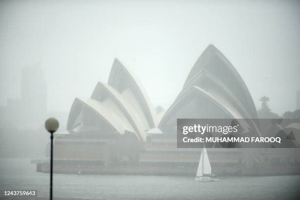 Yacht sails next to the Opera House while it rains in Sydney on October 6, 2022.