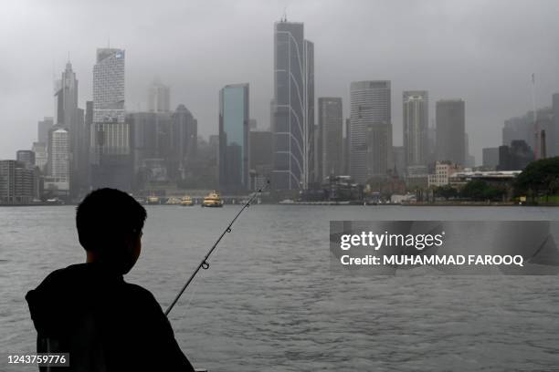 Man fishes in the harbour while it rains in Sydney on October 6, 2022.