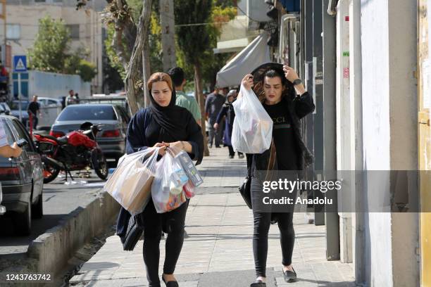 People walk on a sidewalk as anti-government protests following death of Mahsa Amini, a 22-year-old Iranian woman, who was arrested in Tehran on 13...