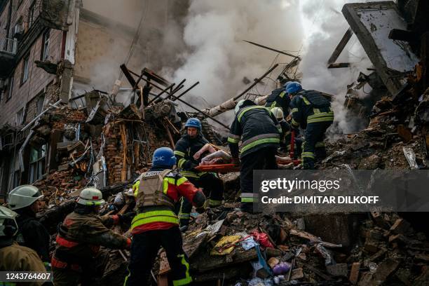 Ukrainian firefighters carry the body of a civilian killed after a strike in Zaporizhzhia on October 6 amid the Russian invasion of Ukraine.