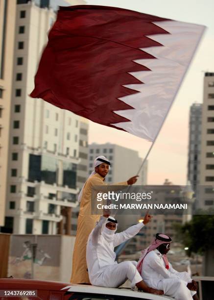 Qataris wave their national flag as they celebrate in Doha on December 3, 2010 a day after the world football's governing body FIFA announced that...