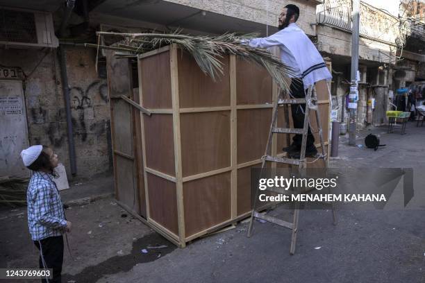 An Ultra Orthodox Jewish man builds a Sukkah, a temporary hut constructed to be used during the week-long Jewish festival of Sukkot, the Feast of...