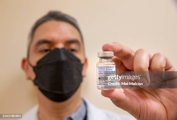 Daniel Carrillo, a pharmacist at AltaMed in Southgate, holds a bottle containing booster doses of the Moderna COVID-19 vaccine, Bivalent, the updated...