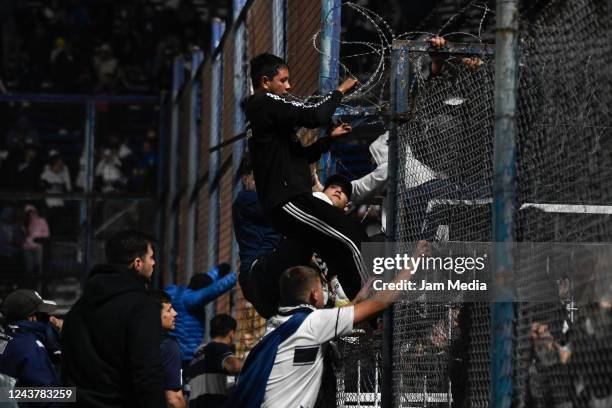Fans of Gimnasia y Esgrima La Plata affected by tear gas jump the fence into the field of play after a match between Gimnasia y Esgrima La Plata and...