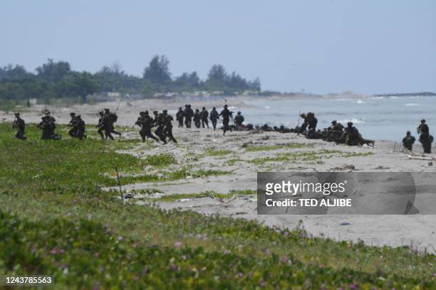 And South Korean marines take positions after disembarking from a US marine landing ship during a joint amphibious landing exercise with their...