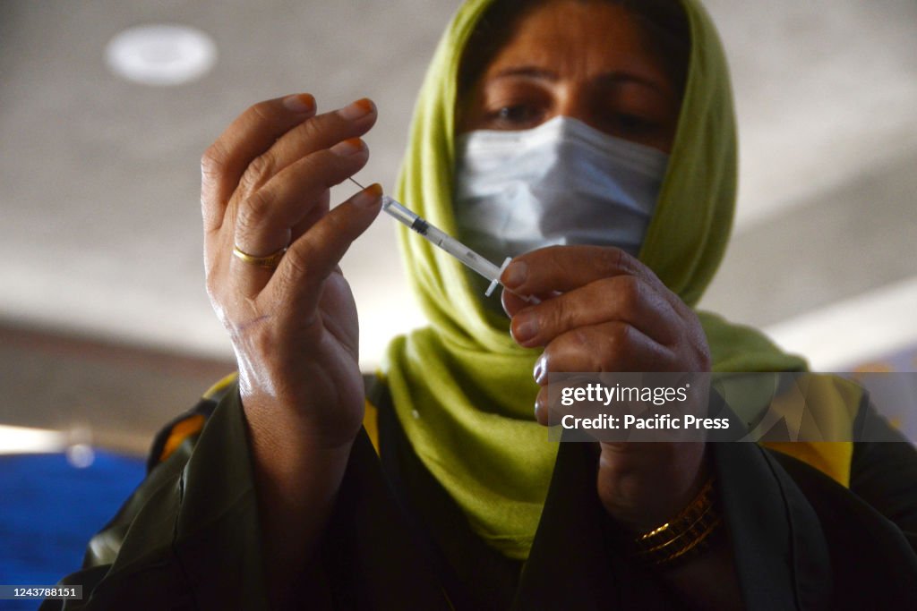 A health worker prepares a typhoid fever vaccine during a...