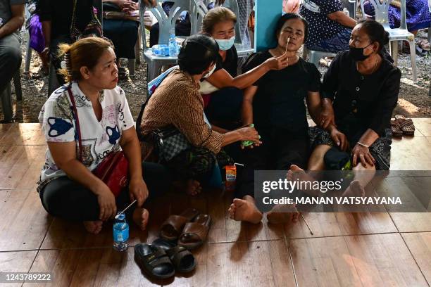 Relative of a victim is attended to, while preparations get underway for the funerals of victims of a mass shooting in a nursery, at Wat Si Uthai...