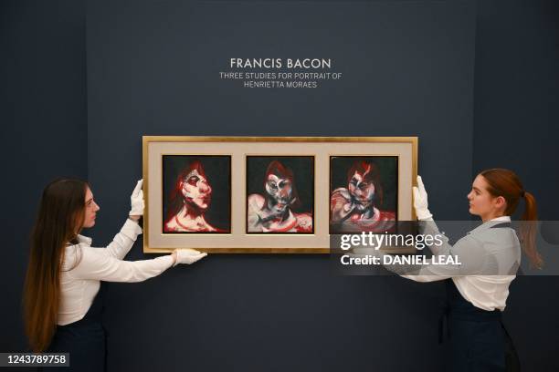 Staff members pose with a triptych by Irish-born British artist Francis Bacon titled "Three Studies for Portrait of Henrietta Moraes" during a press...