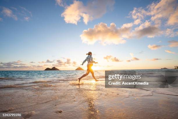 woman runs along the beach at sunrise - beach morning glory stock pictures, royalty-free photos & images