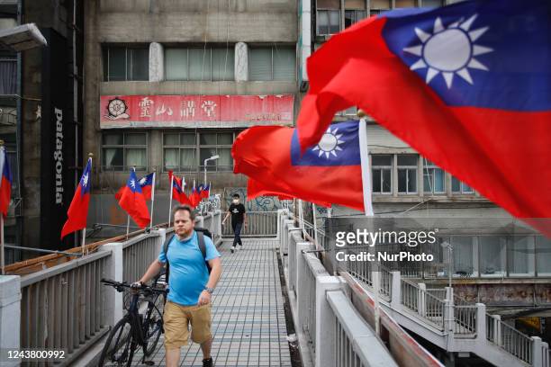 Foreigner with his bike walks across a footbridge in Taipei, where Taiwan flags flutter ahead of the islands national day, amid rising tensions with...