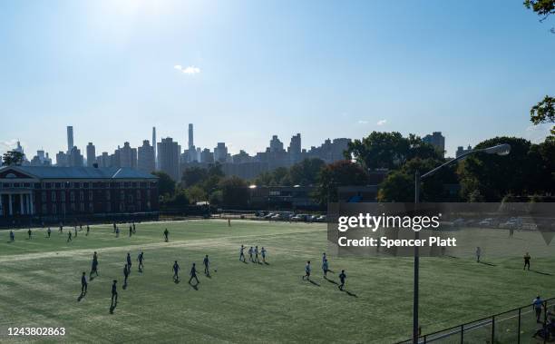 People play soccer near a parking lot on Randall's Island that will be prepared for the arrival of migrants that have arrived from Texas on October...