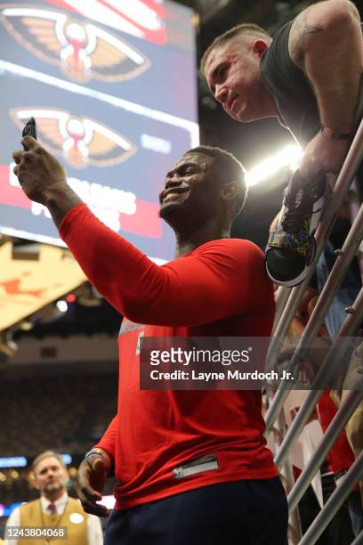 Zion Williamson of the New Orleans Pelicans takes a selfie with a fan before the game against the Detroit Pistons on October 7, 2022 at the Smoothie...